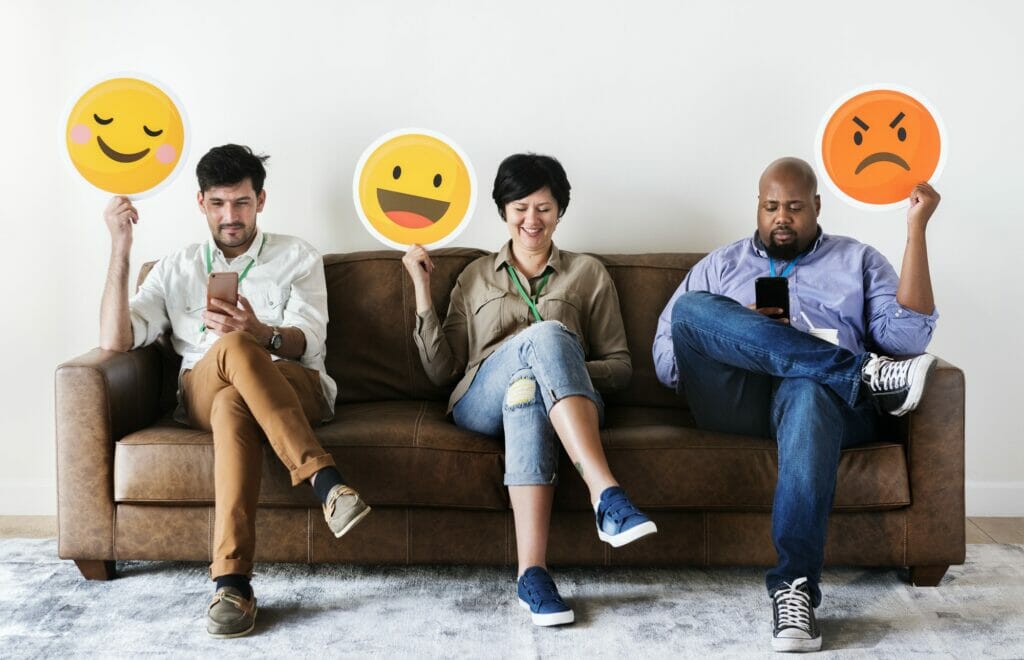 Diverse people sitting and holding emojis logos